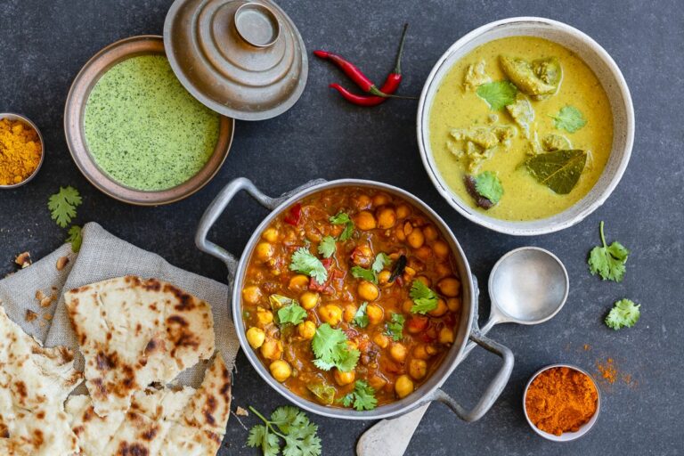 Indische Currys Kochkurs: Rezeptfoto verschiedener Currys, mit Naanbrot. Garniert mit frischem Koriander.