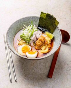 Ramen Kochkurs Wien: Tischsituation Ramenschüsselmit Ei, Limette, Ramen, Frühlingszwiebel und Noriblättern. Stäbchen und Ramen-Löffel daneben.